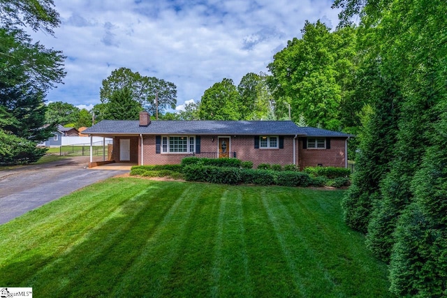 ranch-style house featuring asphalt driveway, a carport, a front yard, and brick siding