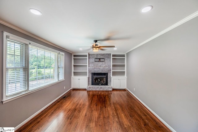 unfurnished living room featuring crown molding, dark wood-style floors, baseboards, ceiling fan, and a fireplace