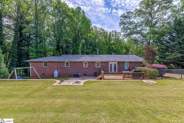 back of property with an outdoor fire pit, a deck, crawl space, a playground, and french doors