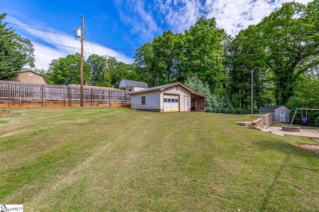 view of yard with an outdoor structure, a detached garage, an outdoor fire pit, and a storage unit