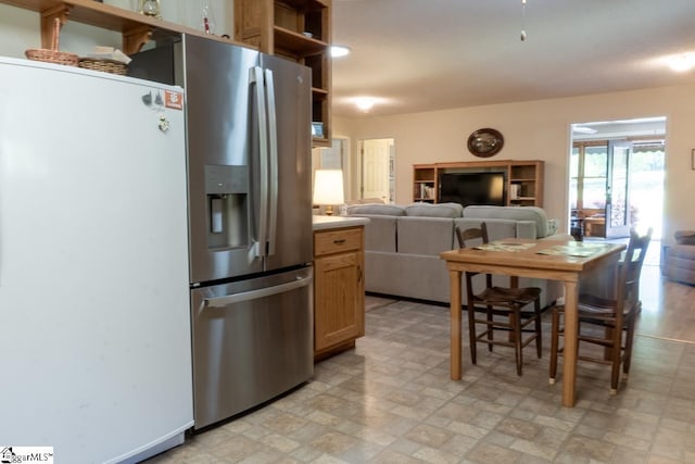 kitchen featuring freestanding refrigerator, open shelves, open floor plan, stainless steel refrigerator with ice dispenser, and light countertops