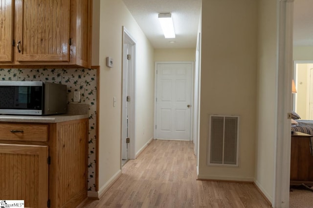 hall featuring light wood-style flooring and baseboards