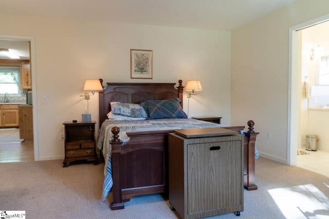 bedroom with light colored carpet, ensuite bathroom, and baseboards