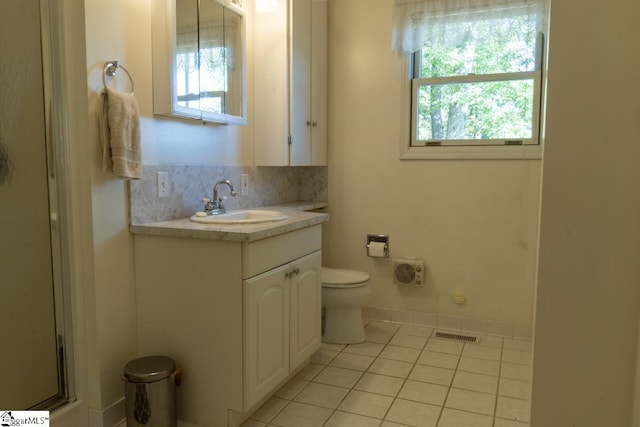 bathroom featuring toilet, tile patterned floors, healthy amount of natural light, and vanity
