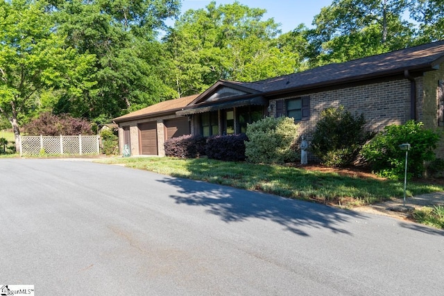 single story home with a garage, asphalt driveway, fence, and brick siding