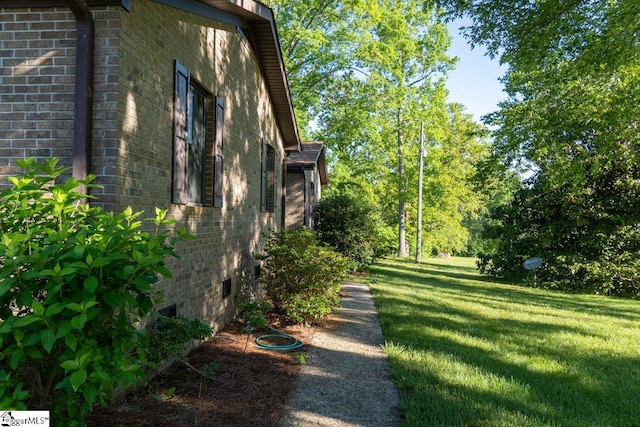view of side of property featuring brick siding and a yard