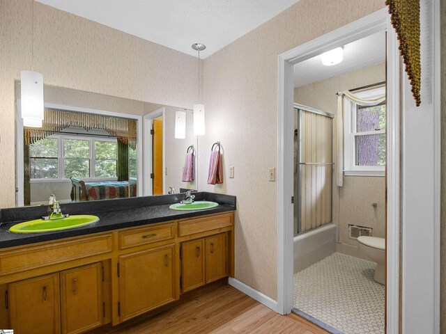 132 Rosecrest Rd, Spartanburg, SC 29303 - full bathroom featuring double vanity, wood finished floors, toilet, bath / shower combo with glass door, and baseboards