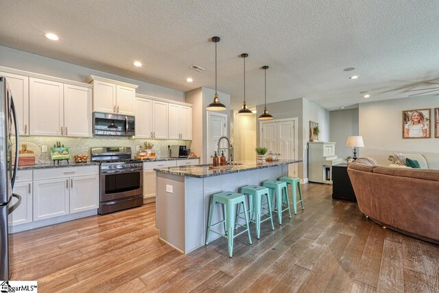 2007 Edwards Lake Rd, Greer, SC 29651 - kitchen featuring stainless steel appliances, a sink, light wood-type flooring, open floor plan, and a kitchen bar