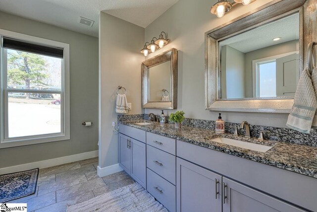 2007 Edwards Lake Rd, Greer, SC 29651 - bathroom with baseboards, plenty of natural light, stone tile flooring, and double vanity