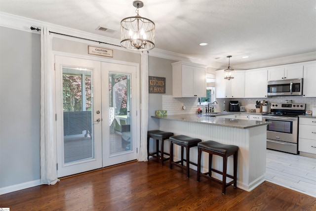 kitchen featuring appliances with stainless steel finishes, french doors, white cabinetry, a sink, and ornamental molding