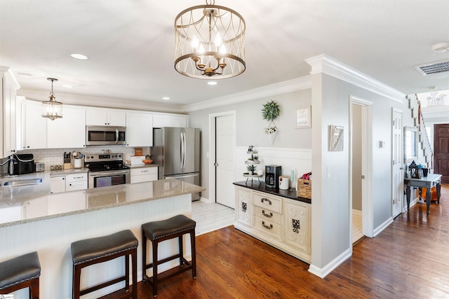 kitchen with stainless steel appliances, a chandelier, backsplash, light stone counters, and ornamental molding