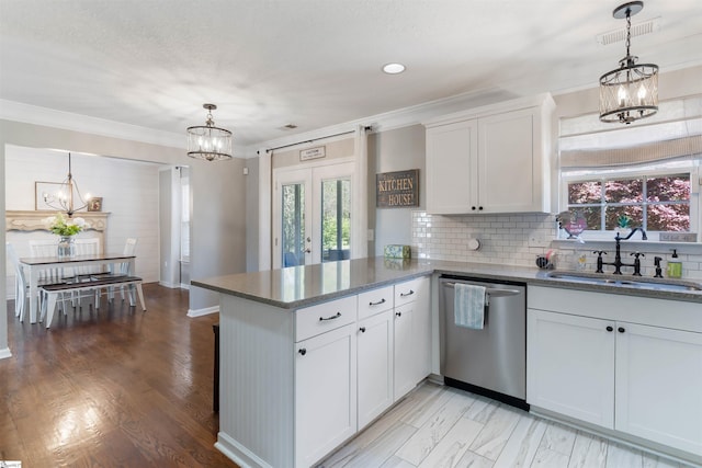kitchen with dishwasher, a sink, a chandelier, a peninsula, and white cabinetry