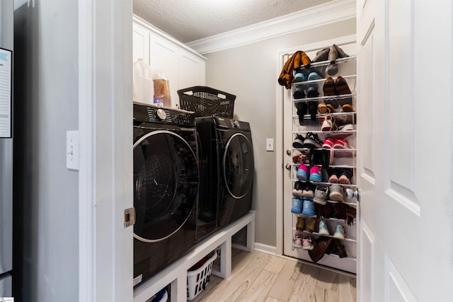 clothes washing area featuring cabinet space, washer and dryer, crown molding, light wood-style flooring, and a textured ceiling