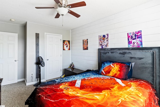 carpeted bedroom with wood walls, baseboards, and a ceiling fan