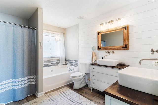 full bathroom featuring wood finished floors, a chandelier, toilet, vanity, and a tub