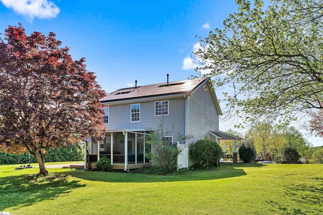 rear view of property with a sunroom, solar panels, and a lawn