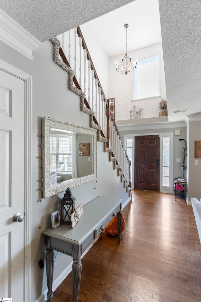 entrance foyer with a chandelier, wood finished floors, stairway, baseboards, and a textured ceiling