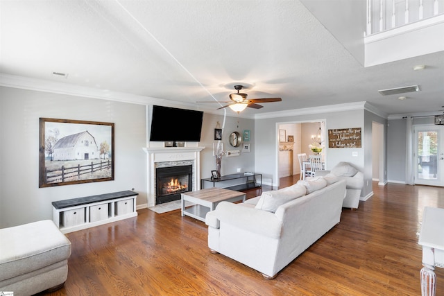 living area with ornamental molding, ceiling fan, wood finished floors, a fireplace with flush hearth, and baseboards