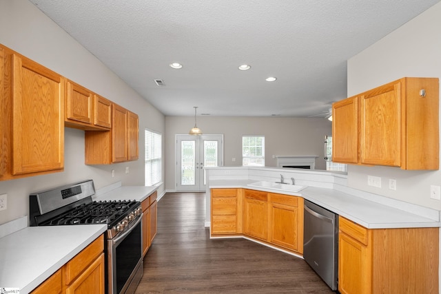 kitchen featuring stainless steel appliances, a peninsula, recessed lighting, dark wood finished floors, and light countertops