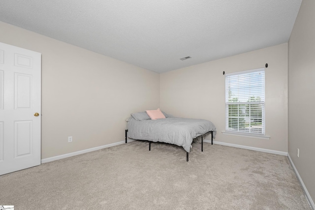 bedroom with carpet floors, baseboards, and a textured ceiling