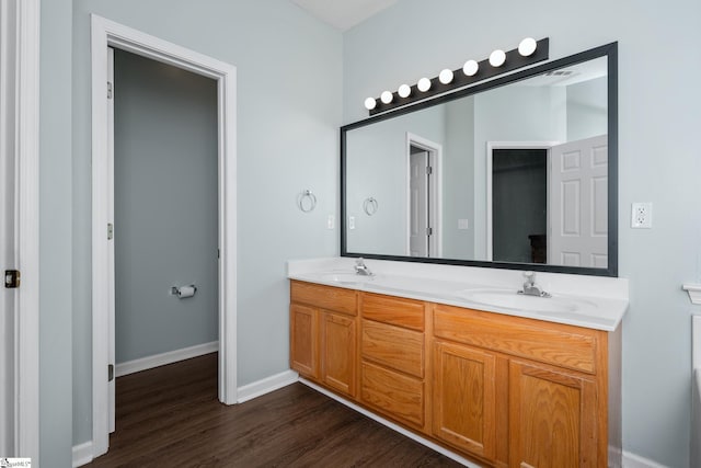 full bathroom featuring wood finished floors, double vanity, and baseboards