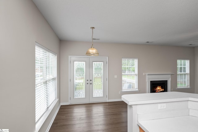 doorway to outside featuring french doors, dark wood-type flooring, a lit fireplace, and baseboards
