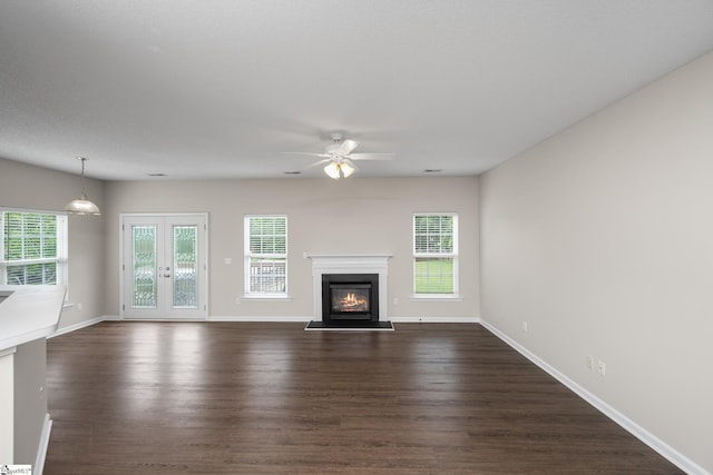 unfurnished living room with a ceiling fan, a glass covered fireplace, dark wood finished floors, and baseboards