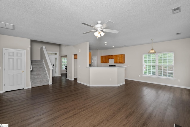 unfurnished living room with dark wood finished floors, a ceiling fan, a textured ceiling, and baseboards