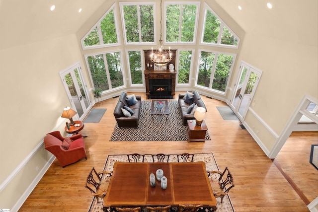 201 King Eider Way, Taylors, SC 29687 - living area with high vaulted ceiling, a chandelier, baseboards, light wood-style flooring, and a warm lit fireplace