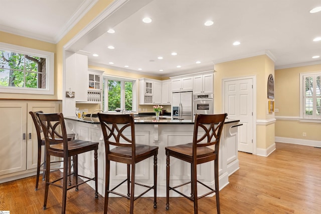 201 King Eider Way, Taylors, SC 29687 - kitchen featuring appliances with stainless steel finishes, a peninsula, a breakfast bar, light wood-style floors, and glass insert cabinets