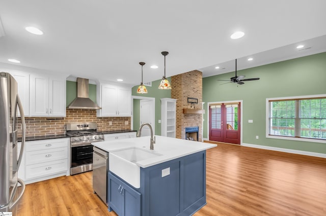 130 Windjammer Way, Anderson, SC 29626 - kitchen with wall chimney range hood, appliances with stainless steel finishes, a fireplace, a ceiling fan, and open floor plan