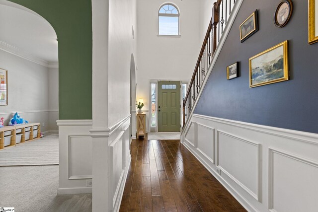 706 Airdale Ln, Simpsonville, SC 29680 - entrance foyer featuring arched walkways, dark wood-style flooring, wainscoting, a decorative wall, and crown molding