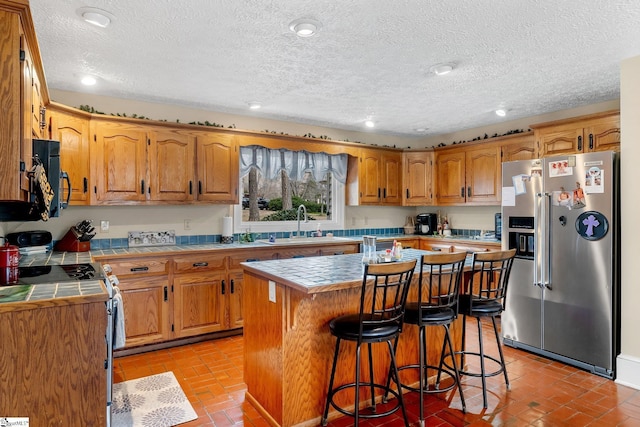 416 Ashley Downs, Anderson, SC 29621 - kitchen featuring stainless steel refrigerator with ice dispenser, tile countertops, range with electric cooktop, a kitchen breakfast bar, and a textured ceiling