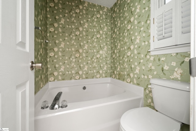 bathroom with wallpapered walls, toilet, and a bath