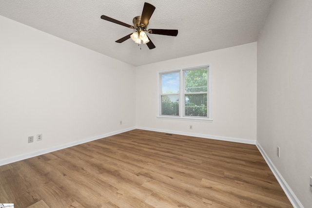 spare room featuring wood finished floors, ceiling fan, a textured ceiling, and baseboards