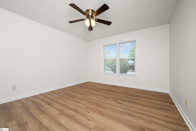 spare room featuring light wood-style flooring, a ceiling fan, baseboards, and a textured ceiling