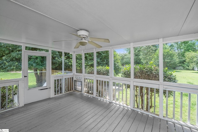 unfurnished sunroom featuring ceiling fan and view of scattered trees