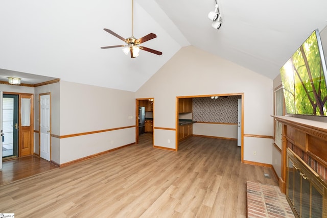 unfurnished living room with a ceiling fan, baseboards, lofted ceiling, and light wood-type flooring