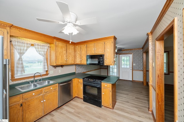 kitchen with black appliances, a sink, wallpapered walls, a ceiling fan, and ornamental molding