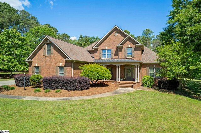 traditional-style house featuring brick siding, covered porch, and a front yard
