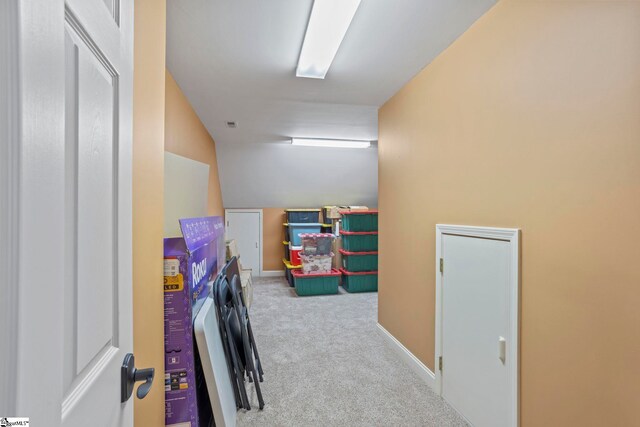 hallway with carpet, vaulted ceiling, and baseboards