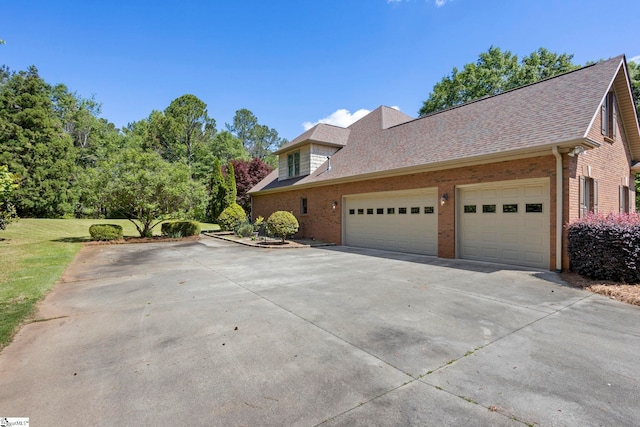 view of side of property with brick siding, driveway, an attached garage, and a shingled roof