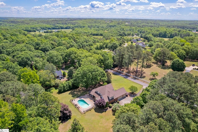 drone / aerial view of a forest and a pool area