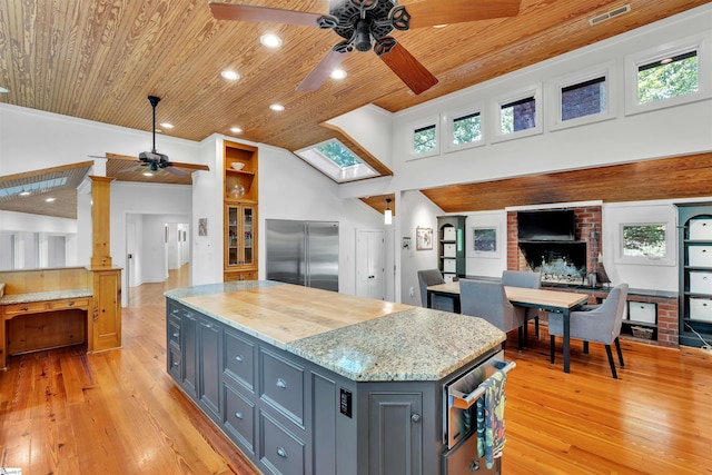 kitchen with ceiling fan, built in refrigerator, wood ceiling, a kitchen island, and light wood finished floors