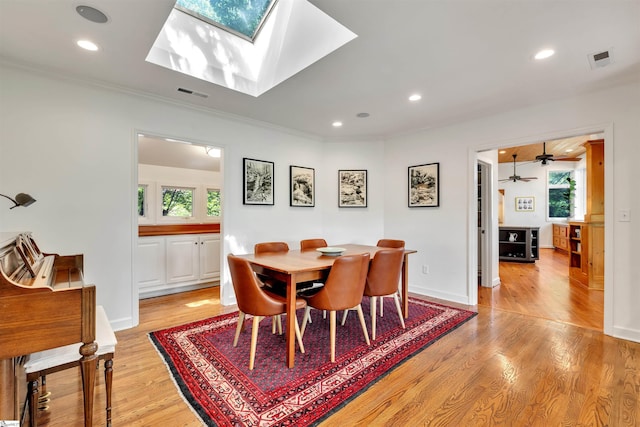 dining area with light wood-type flooring, ornamental molding, recessed lighting, a skylight, and ceiling fan