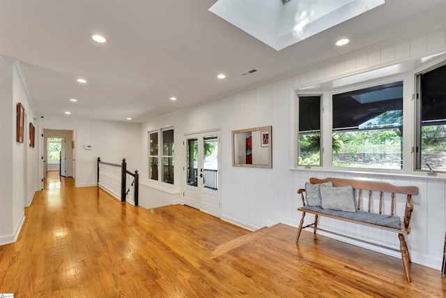 hallway featuring crown molding, recessed lighting, a skylight, light wood-type flooring, and an upstairs landing