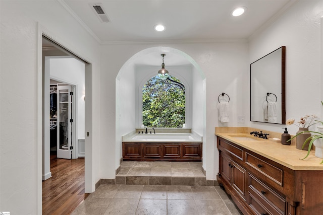 full bath featuring ornamental molding, a bath, baseboards, vanity, and a spacious closet