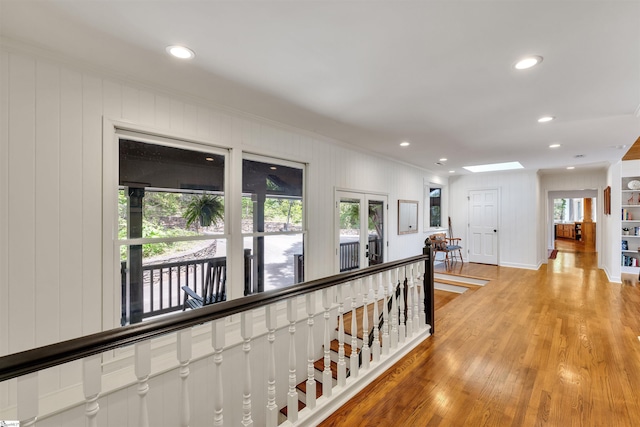 hall featuring an upstairs landing, crown molding, light wood-style flooring, a skylight, and recessed lighting