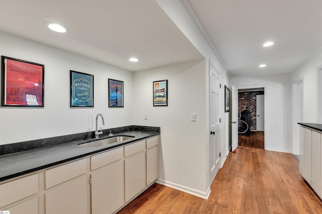 kitchen featuring a sink, dark countertops, light wood finished floors, recessed lighting, and baseboards