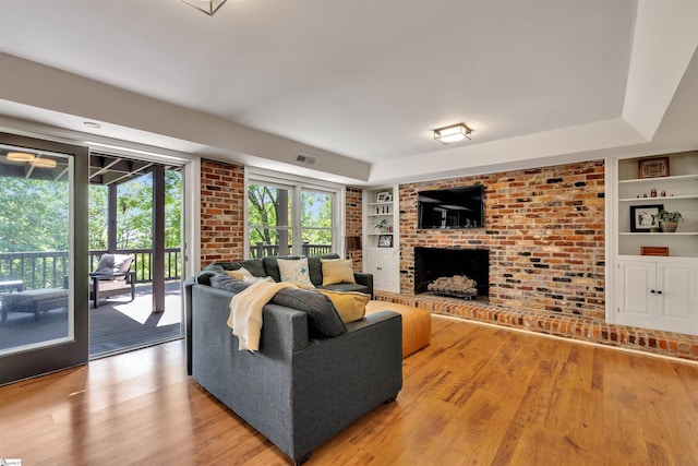 living area featuring built in features, light wood-style flooring, and a fireplace